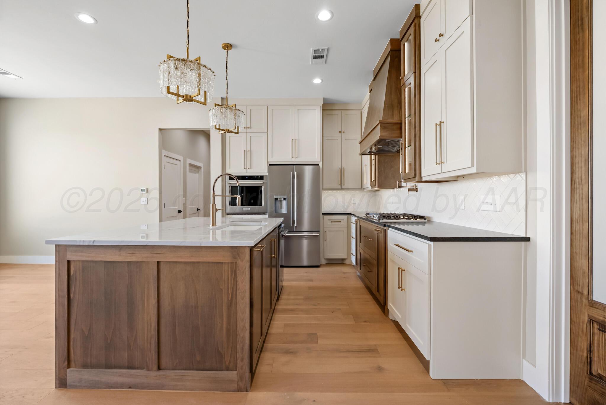 4201 Juniper Springs Road Amarillo, TX 79119 - Photo 6 of 27 a kitchen with stainless steel appliances granite countertop a sink a stove a refrigerator and island with wooden floor