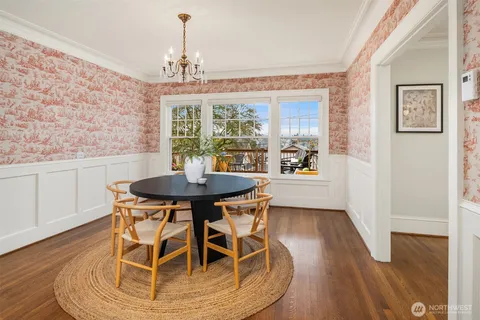 a dining room with wooden floor a chandelier a wooden table and chairs