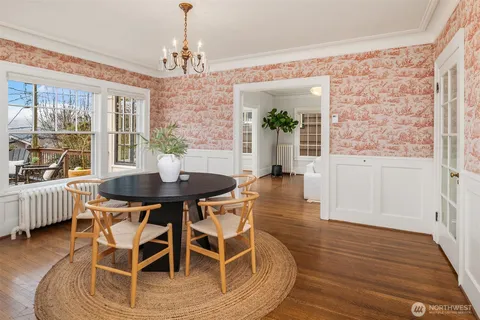 a dining room with wooden floor and large windows