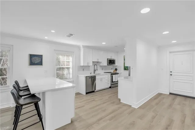 a open kitchen with white cabinets and wooden floor