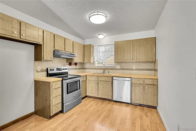 a kitchen with granite countertop a sink cabinets stainless steel appliances and a counter space