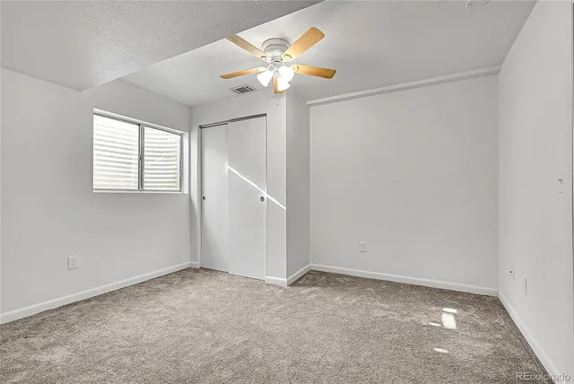 an empty room with windows and fan