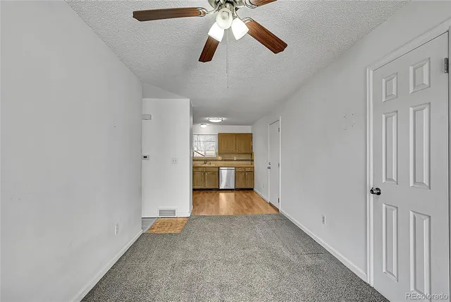 a view of a room with an empty space and a kitchen