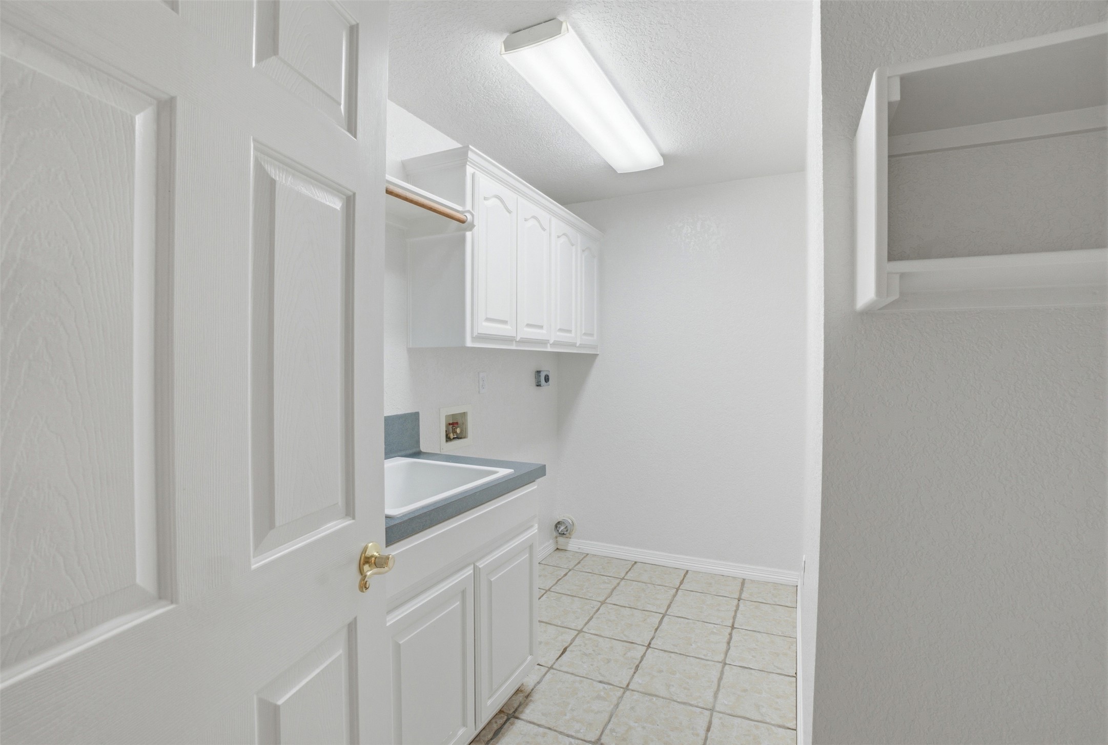 1301 County Road 262 Georgetown, TX 78633 - Photo 22 of 39 Laundry room with tiled flooring, white cabinetry, a utility sink with a grey countertop, and overhead fluorescent lighting