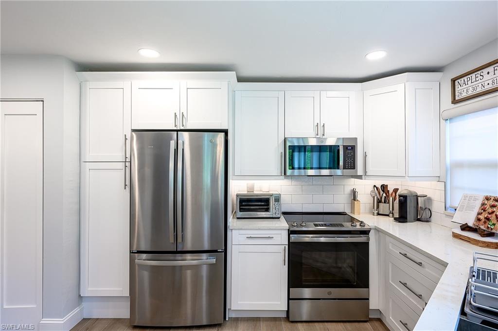 719 Reef Point Circle, Unit 13 Naples, FL 34108 - Photo 11 of 29 a kitchen with refrigerator a microwave a sink and cabinets