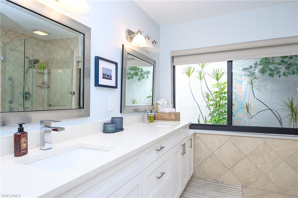 719 Reef Point Circle, Unit 13 Naples, FL 34108 - Photo 18 of 29 a bathroom with a sink and a large mirror next to a window