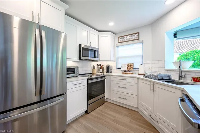 a kitchen with white cabinets stainless steel appliances and window