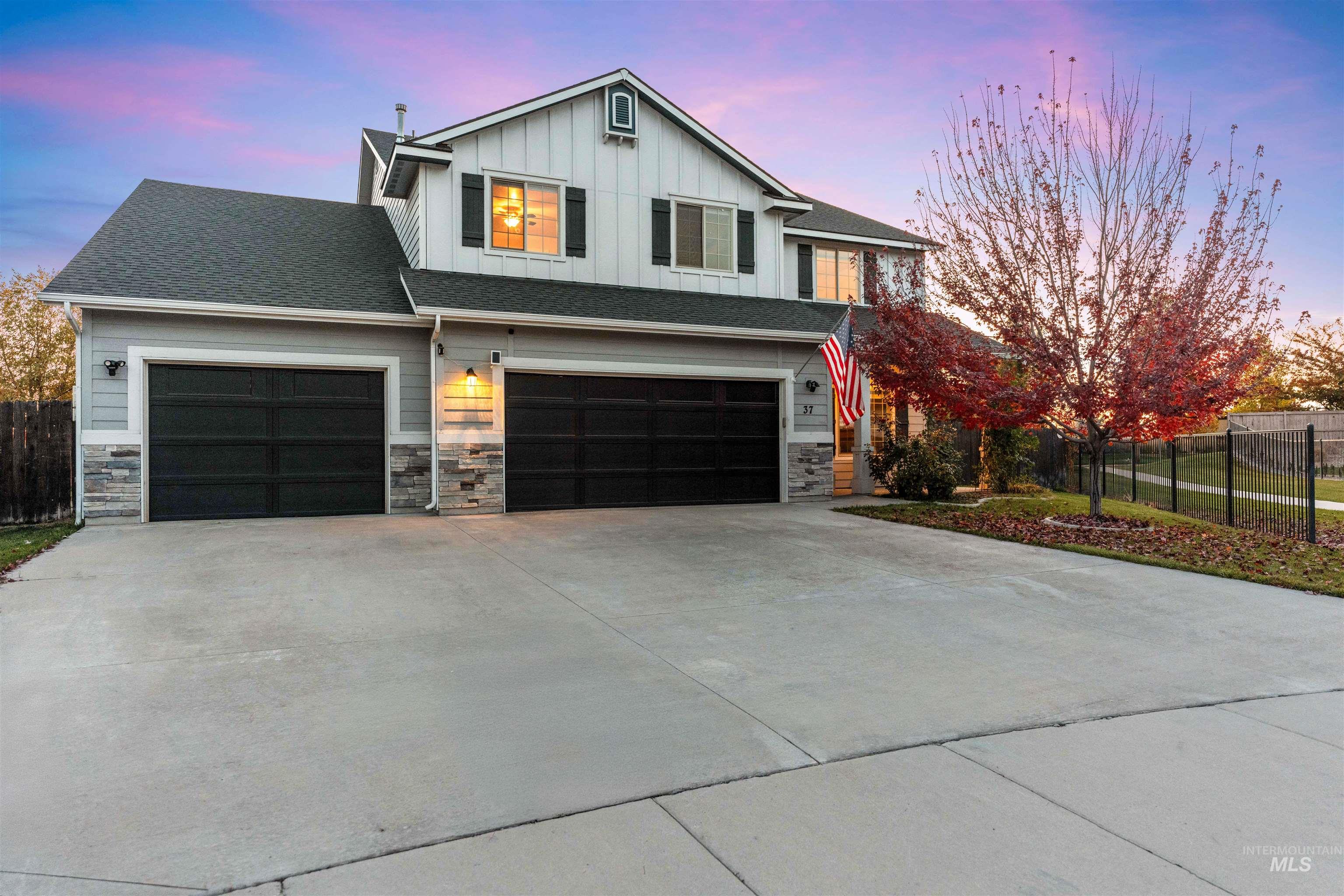 View of front of home featuring board and batten siding, concrete driveway, an attached garage, stone siding, and roof with shingles