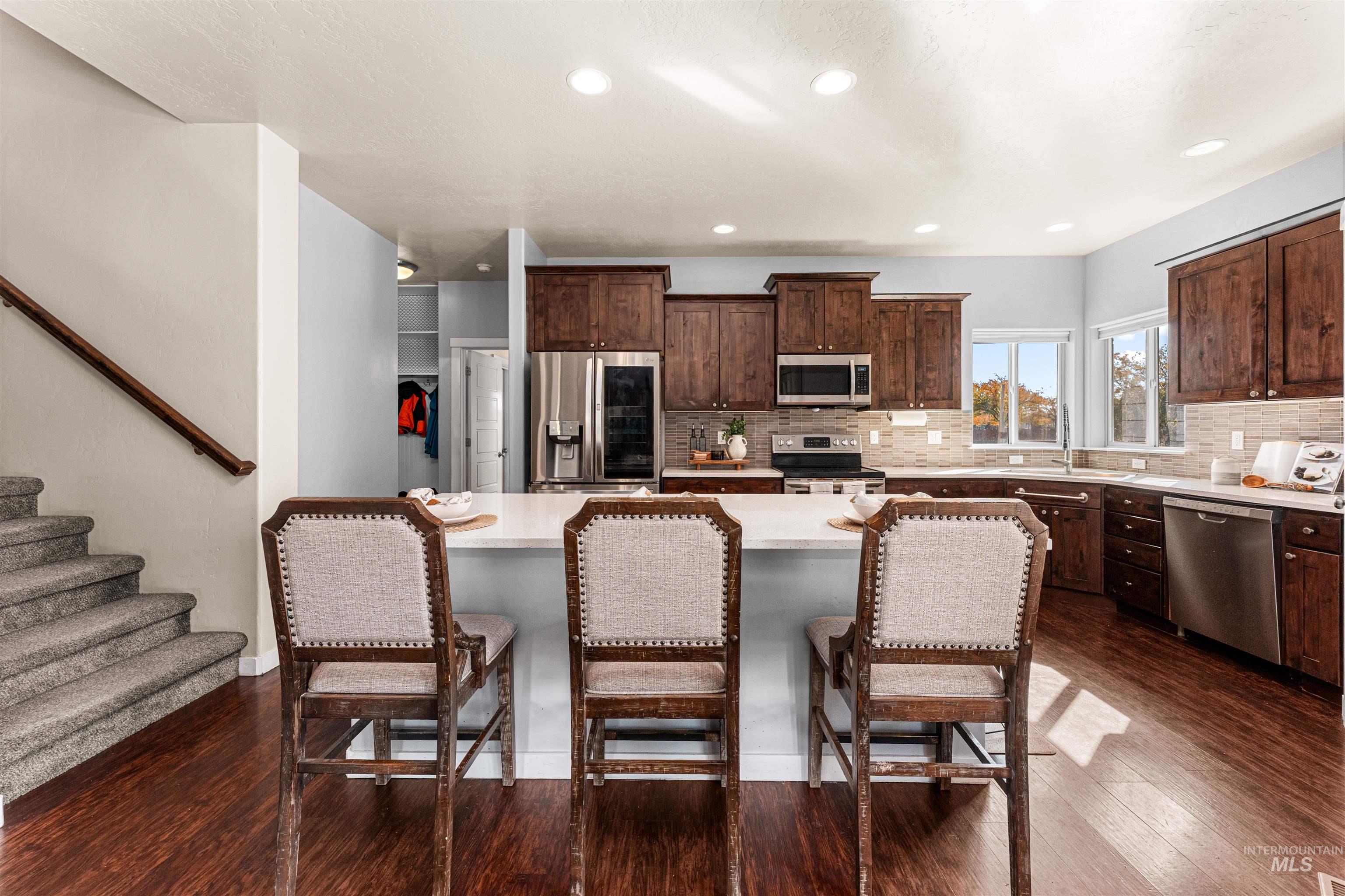 37 East Ensenada Drive Meridian, ID 83646 - Photo 14 of 46 Kitchen with dark brown cabinets, dark wood finished floors, stainless steel appliances, decorative backsplash, and a center island