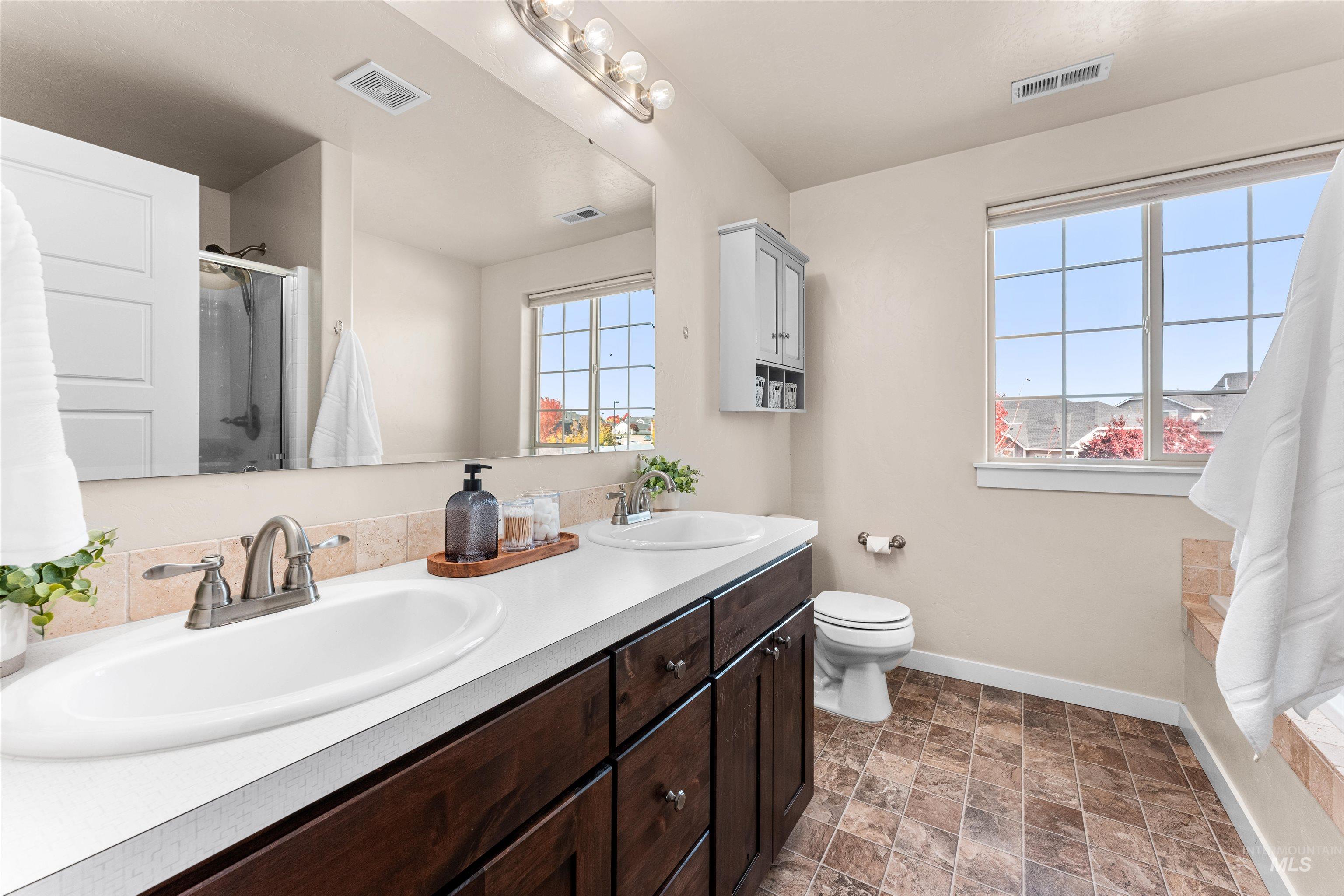 37 East Ensenada Drive Meridian, ID 83646 - Photo 27 of 46 Bathroom featuring a stall shower, double vanity, and stone finish flooring