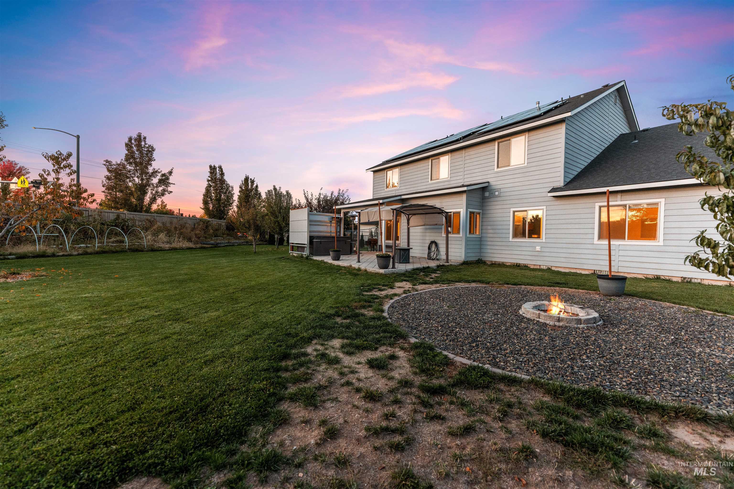 37 East Ensenada Drive Meridian, ID 83646 - Photo 44 of 46 Back of house featuring a fire pit, a patio, solar panels, a fenced backyard, and a shingled roof