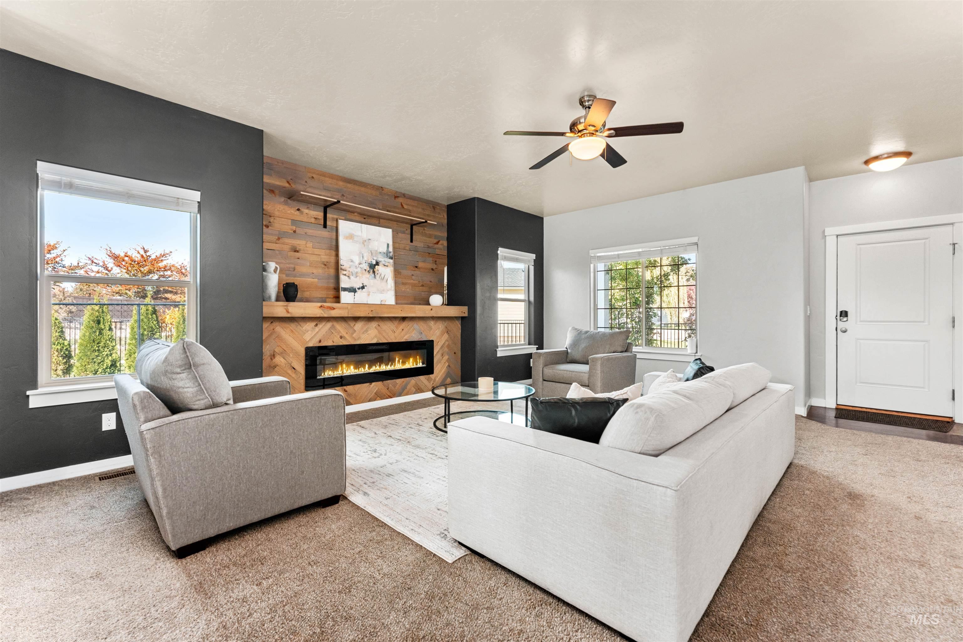 37 East Ensenada Drive Meridian, ID 83646 - Photo 6 of 46 Carpeted living area with a glass covered fireplace, wood walls, and a ceiling fan