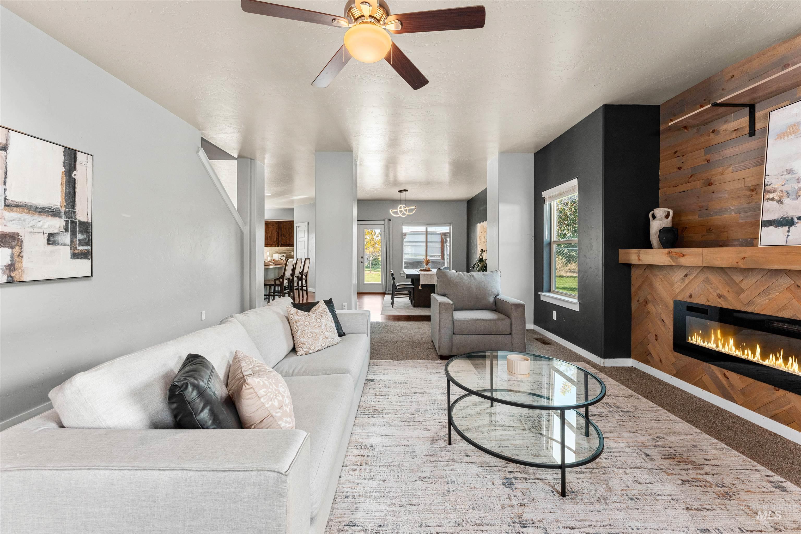 37 East Ensenada Drive Meridian, ID 83646 - Photo 7 of 46 Carpeted living area featuring a glass covered fireplace, ceiling fan, and wooden walls