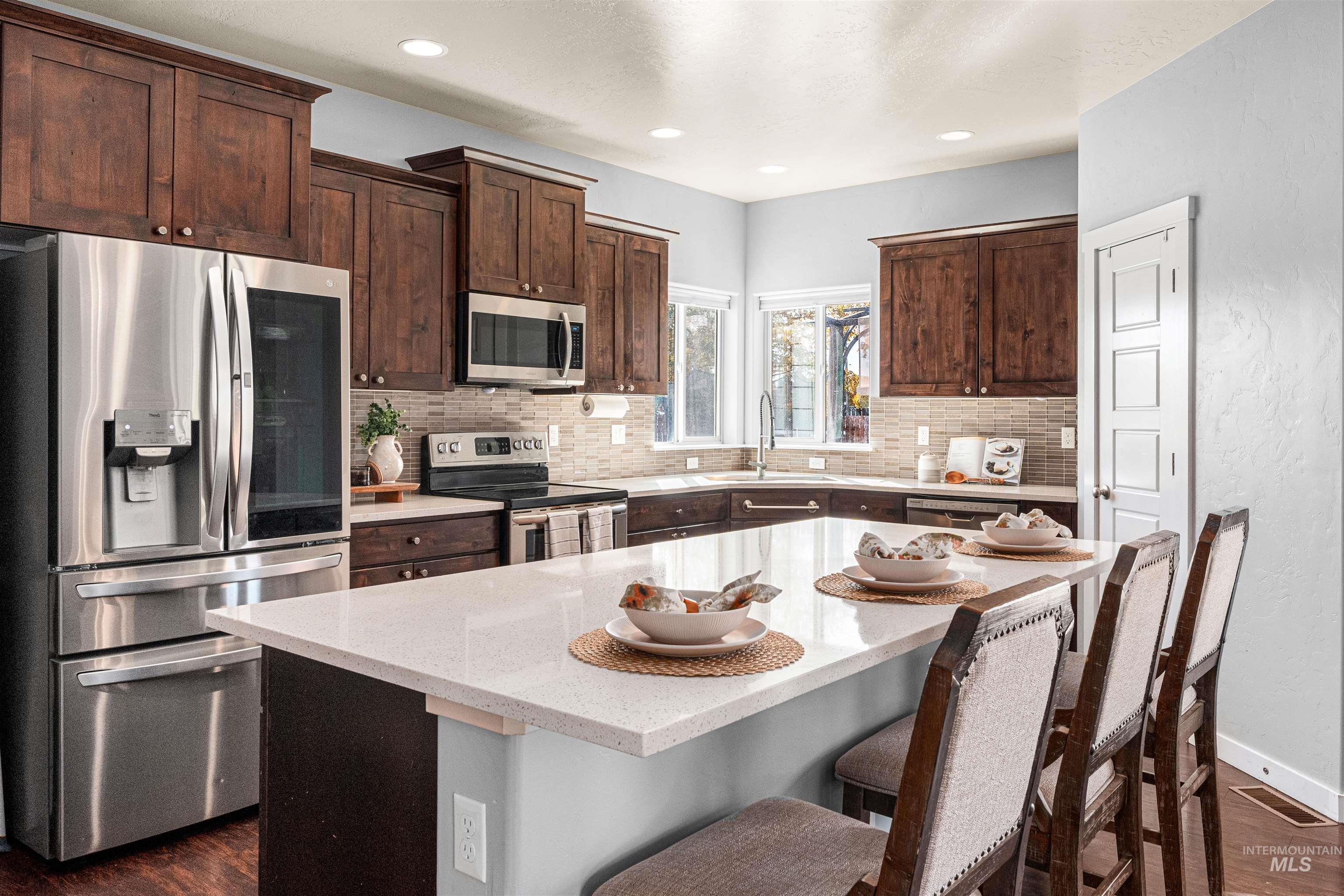 37 East Ensenada Drive Meridian, ID 83646 - Photo 8 of 46 Kitchen featuring appliances with stainless steel finishes, dark wood finished floors, dark brown cabinetry, and recessed lighting