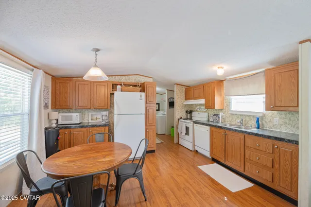 a kitchen with stainless steel appliances a dining table chairs stove refrigerator and cabinets