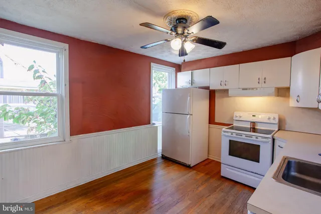 a view of a kitchen with a refrigerator a ceiling fan and wooden floor