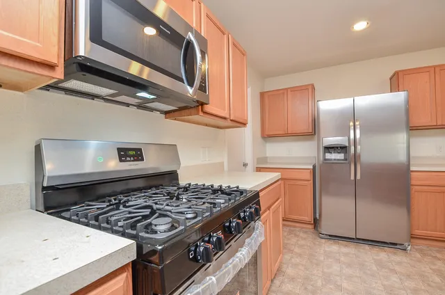 a kitchen with stainless steel appliances granite countertop a stove a refrigerator and a microwave