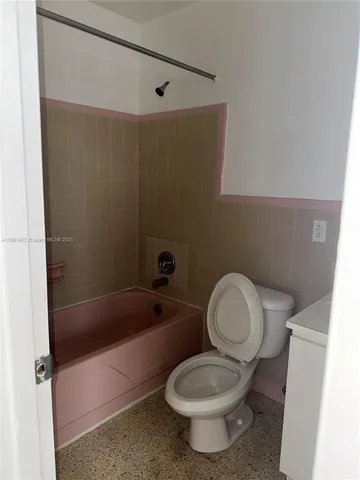 a white toilet sitting next to a bath tub