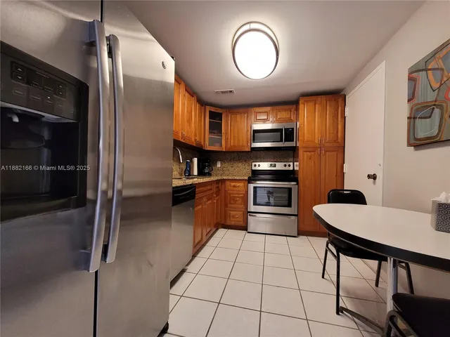 a kitchen with stainless steel appliances granite countertop a stove top oven a sink and a refrigerator