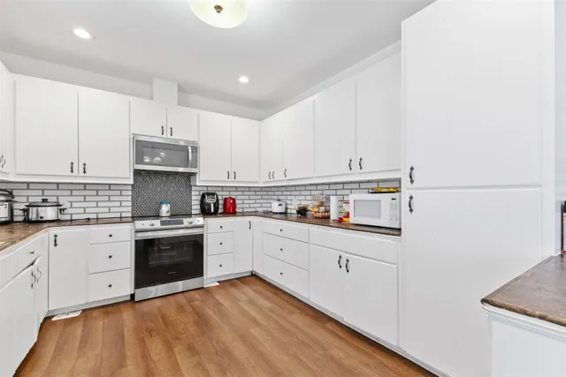 a large kitchen with cabinets stainless steel appliances and wooden floor