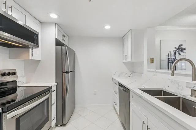 a kitchen with stainless steel appliances a refrigerator a sink a stove a table and chairs