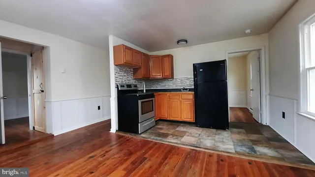 a kitchen with granite countertop wooden floors and a refrigerator