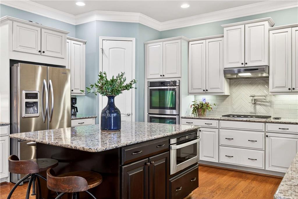 340 Scott Farm Drive Powder Springs, GA 30127 - Photo 19 of 59 a kitchen with stainless steel appliances granite countertop a kitchen island hardwood floor stove and cabinets