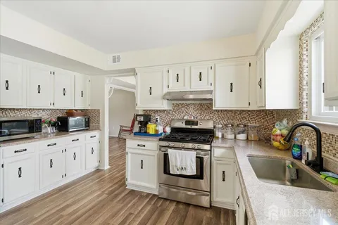 a kitchen with granite countertop a sink a stove and cabinets