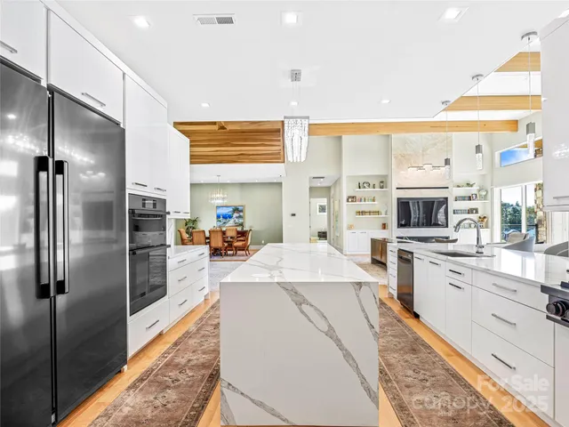 a large kitchen with stainless steel appliances kitchen island a large counter top and a refrigerator
