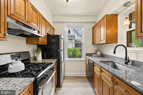 a kitchen with stainless steel appliances granite countertop a stove a sink dishwasher and cabinets with wooden floor