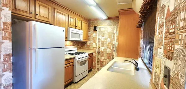 a kitchen with stainless steel appliances granite countertop a refrigerator a stove and a sink with wooden cabinets
