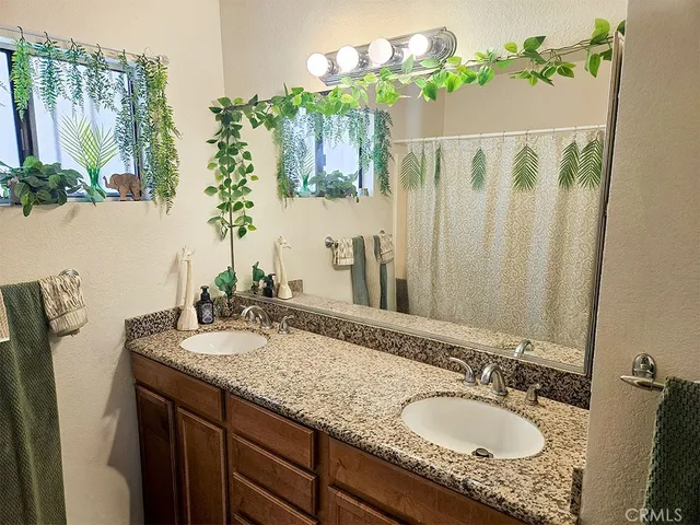a bathroom with a granite countertop sink a mirror and a shower