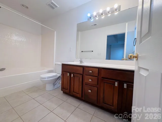 a spacious bathroom with a granite countertop sink a toilet a mirror and bathtub