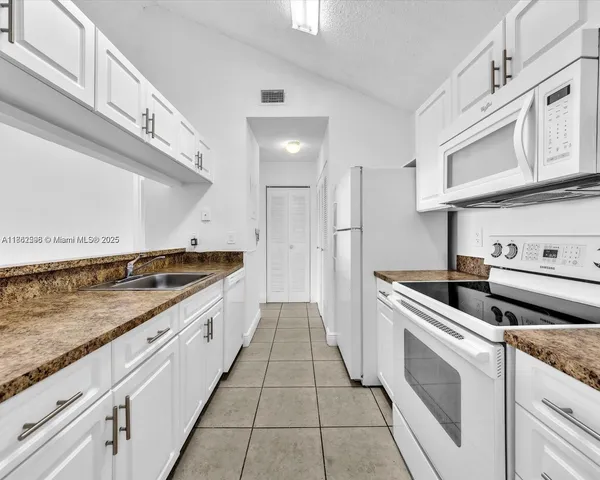 a kitchen with white cabinets and white appliances