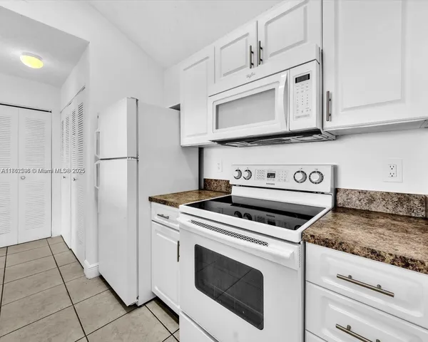 a view of an empty room and kitchen with window