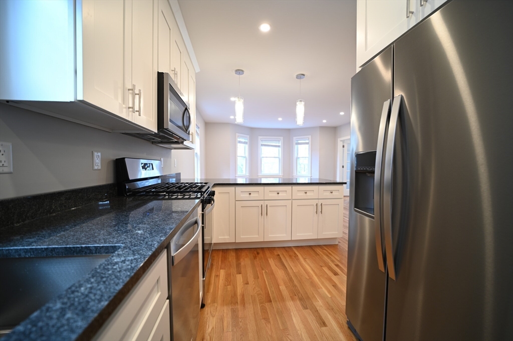 19 Roberts Street, Unit 3 Brookline, MA 02445 - Photo 3 of 10 a kitchen with stainless steel appliances granite countertop a refrigerator a stove and a sink with wooden floor