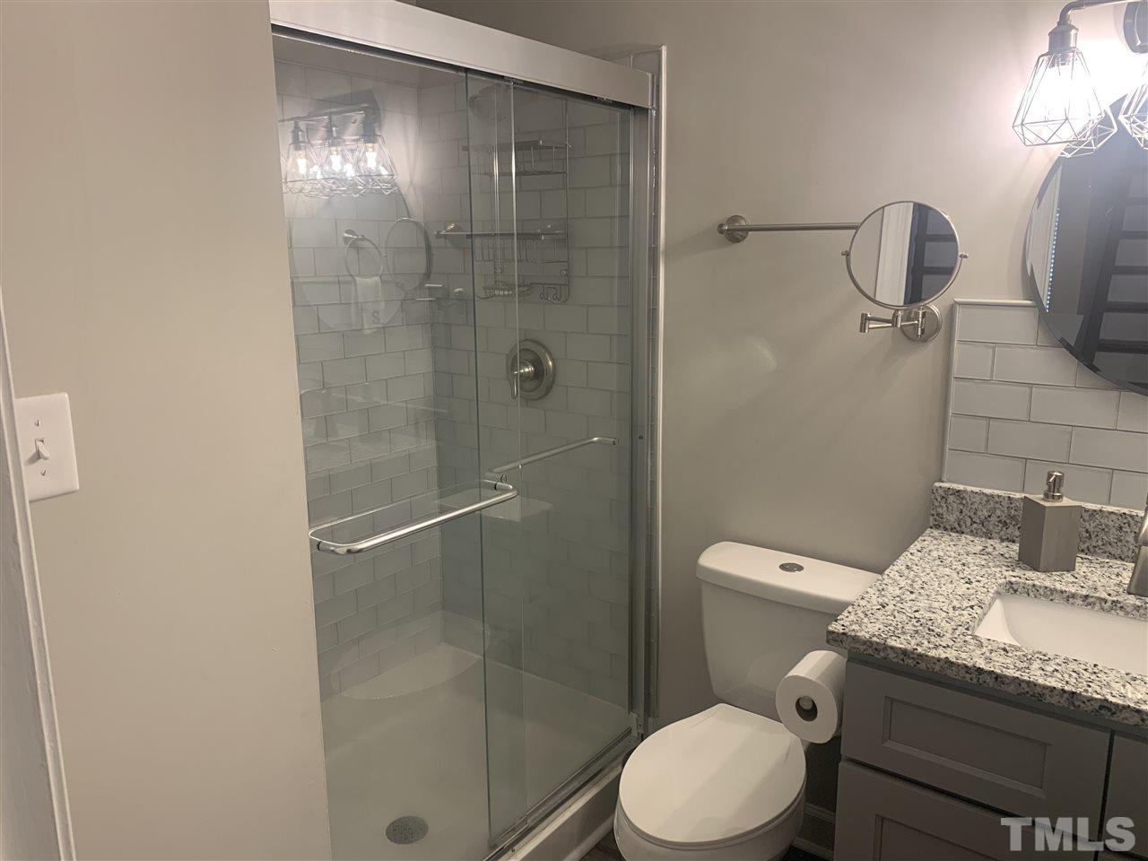 7731 Kelley Court Raleigh, NC 27615 - Photo 12 of 14 a bathroom with a granite countertop toilet and a shower