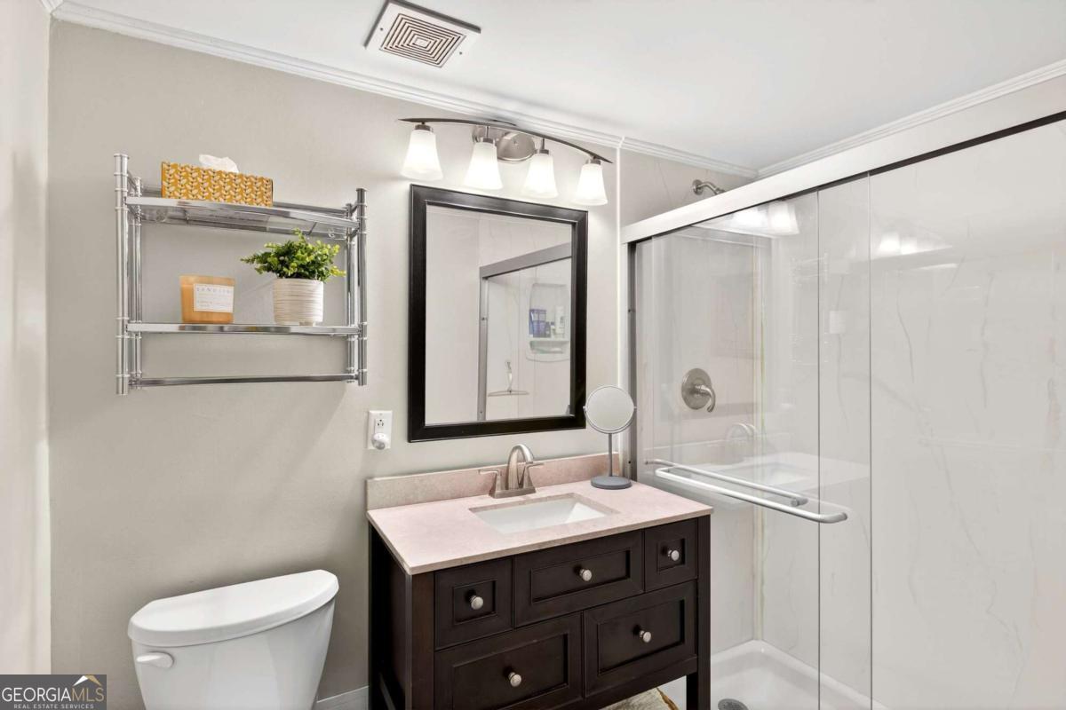 2285 Peachtree Road, Unit 1106 Atlanta, GA 30309 - Photo 16 of 27 a bathroom with a granite countertop sink a toilet a mirror and shower