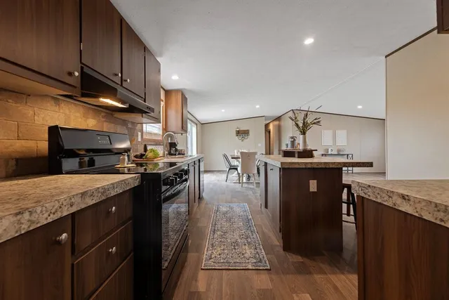 a kitchen with stainless steel appliances granite countertop a sink a stove and a wooden floors