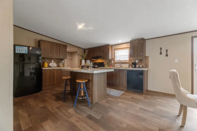 a kitchen with stainless steel appliances kitchen island granite countertop a refrigerator and a stove top oven