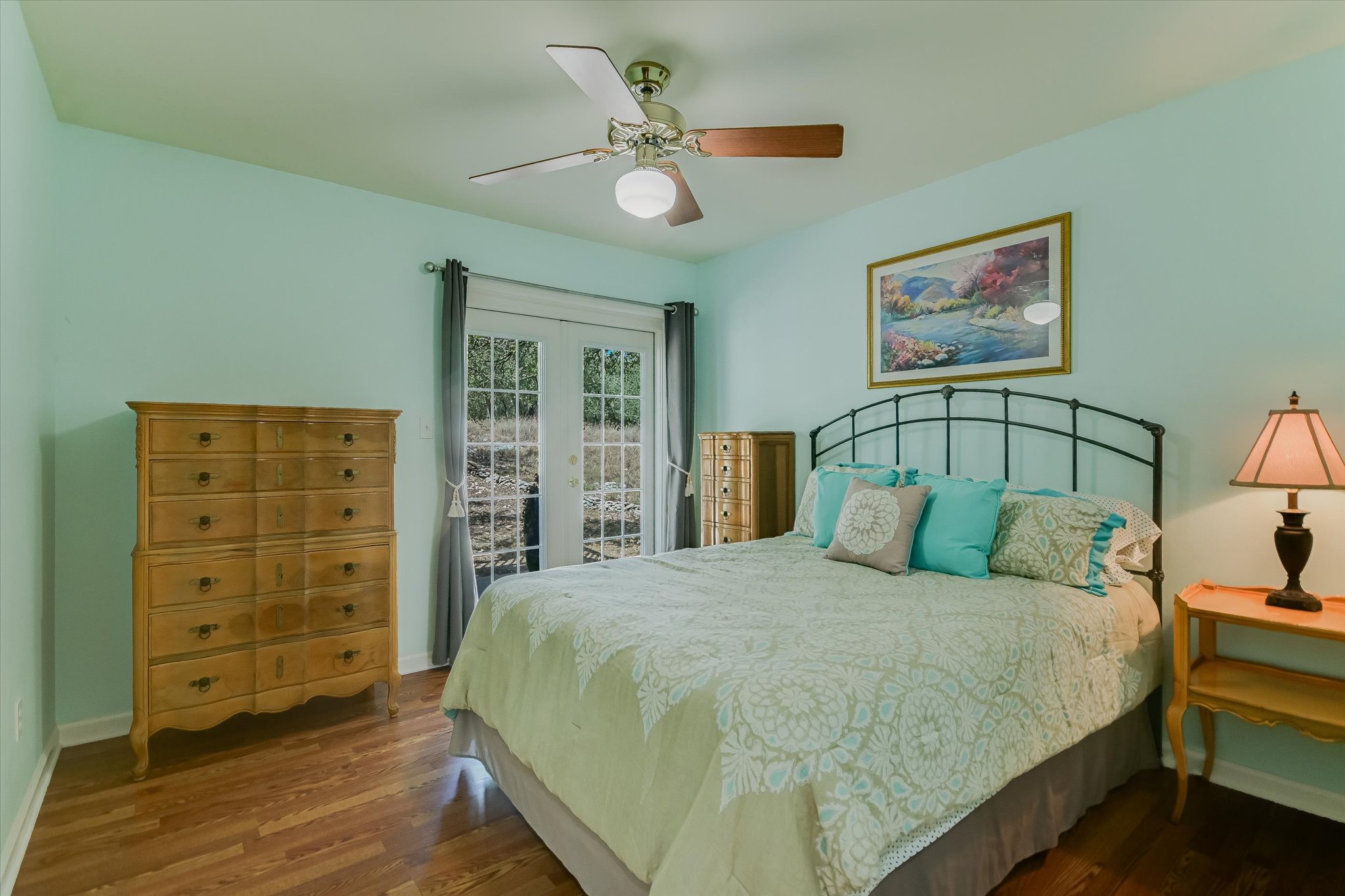 401 North Rainbow Ranch Road Wimberley, TX 78676 - Photo 15 of 39 Rich hardwood floors anchor this inviting bedroom, complete with glass-paneled doors opening to the outdoors.