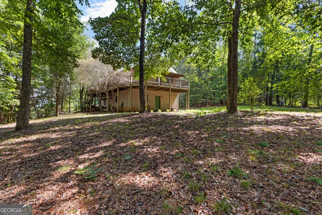 an aerial view of a houses with outdoor space and trees all around