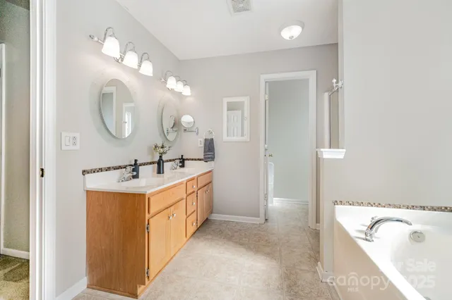 a spacious bathroom with a double vanity sink mirror and bathtub