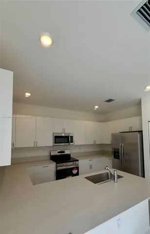 a kitchen with stainless steel appliances a sink a stove a microwave a refrigerator and cabinets