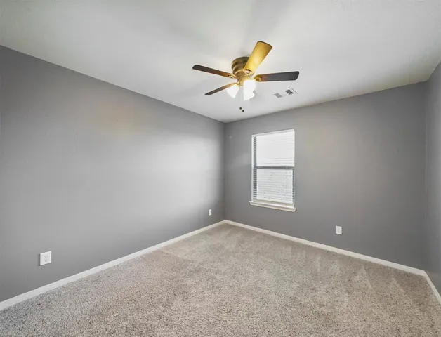 an empty room with windows and fan chandelier fan