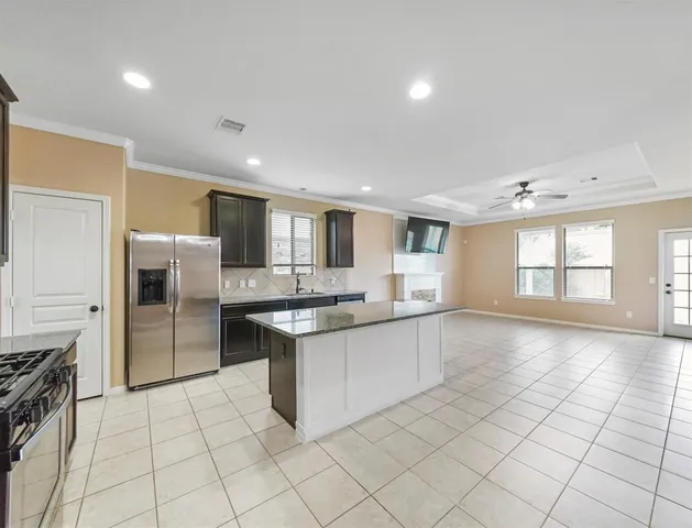 a large kitchen with a stove a sink dishwasher a refrigerator and white cabinets with wooden floor