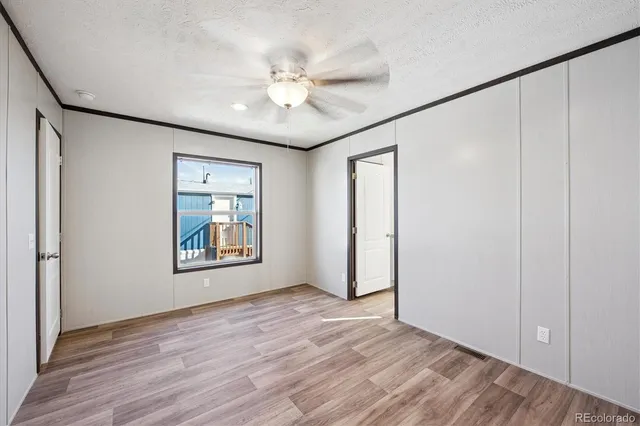 an empty room with wooden floor fan and windows