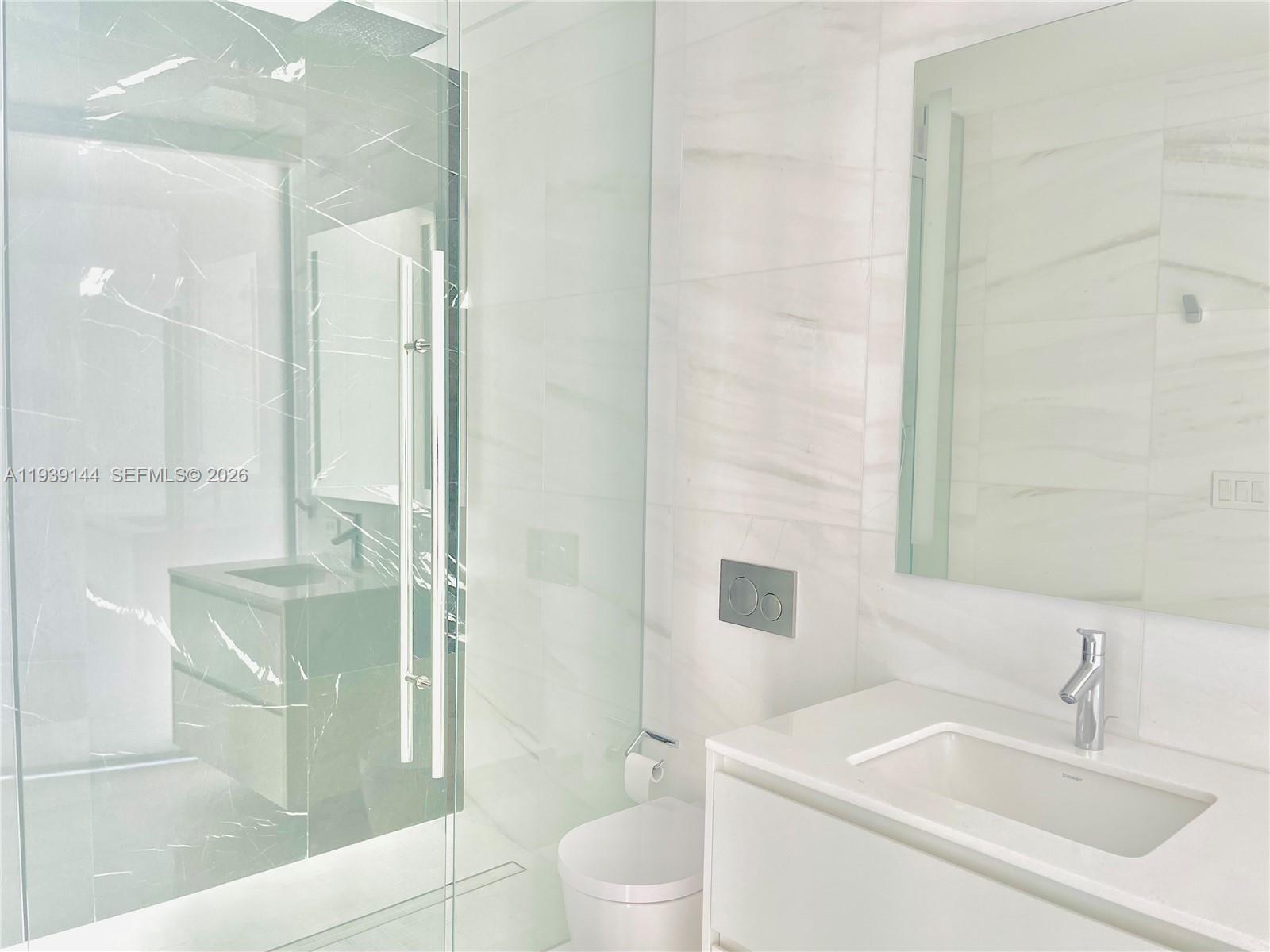 300 Biscayne Blvd Way, Unit 2807 Miami, FL 33131 - Photo 47 of 59 a bathroom with a granite countertop sink a toilet a mirror and shower