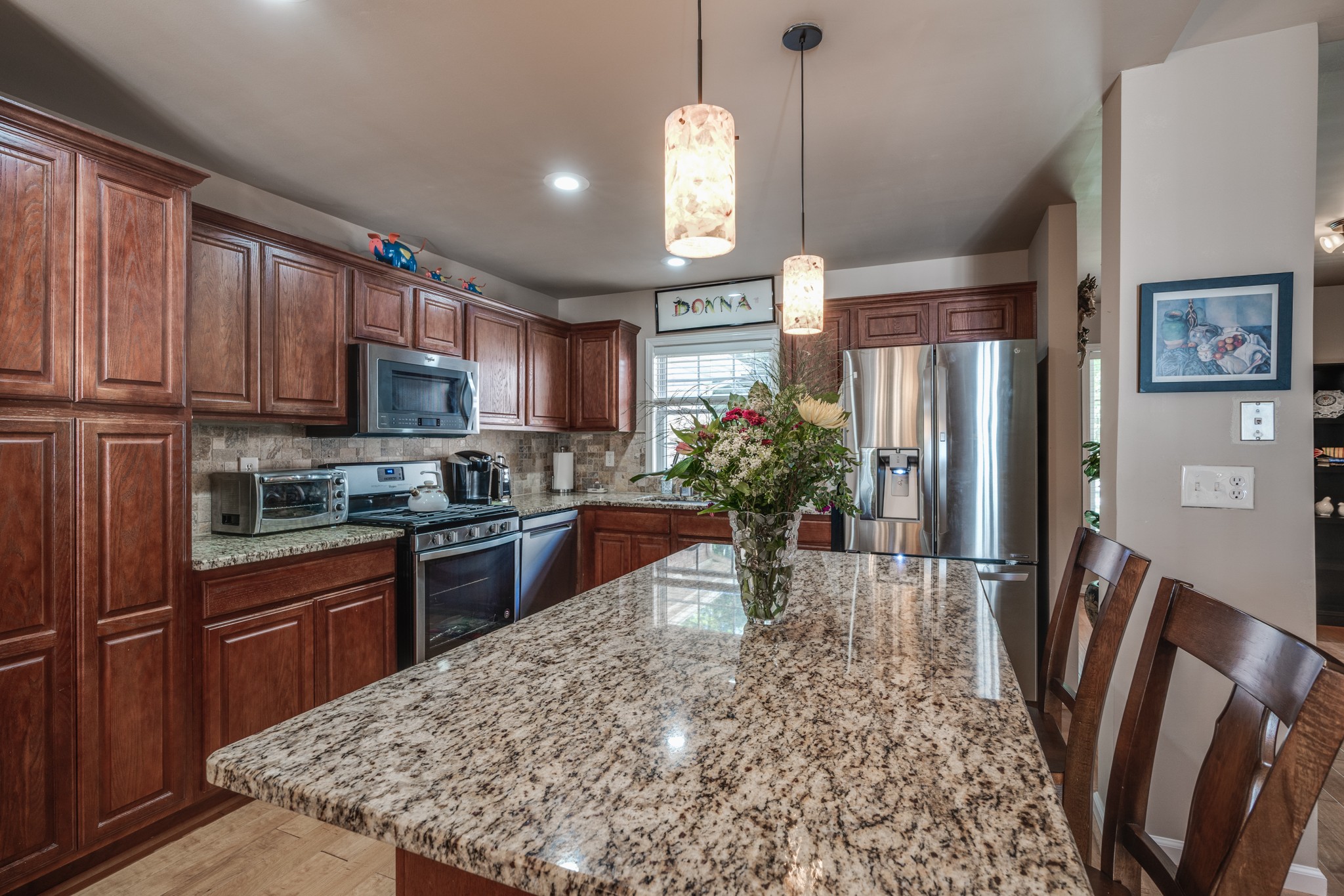 7139 New Hope Road Fairview, TN 37062 - Photo 13 of 41 a kitchen with stainless steel appliances granite countertop a refrigerator a stove a sink a microwave a dining table and chairs with wooden floor