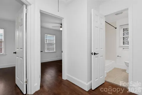 an empty room with wooden floor ceiling fan and windows